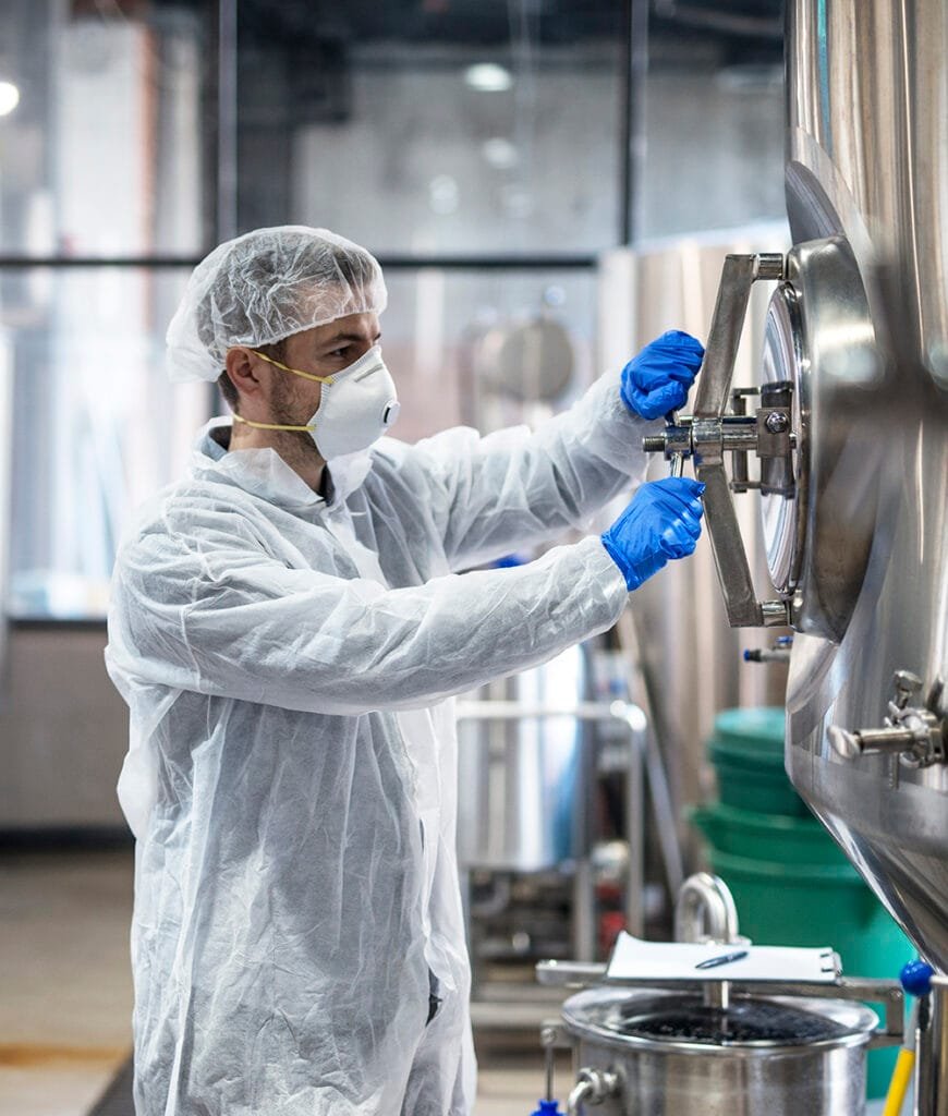 Technologist in protective uniform wearing hairnet mask goggles